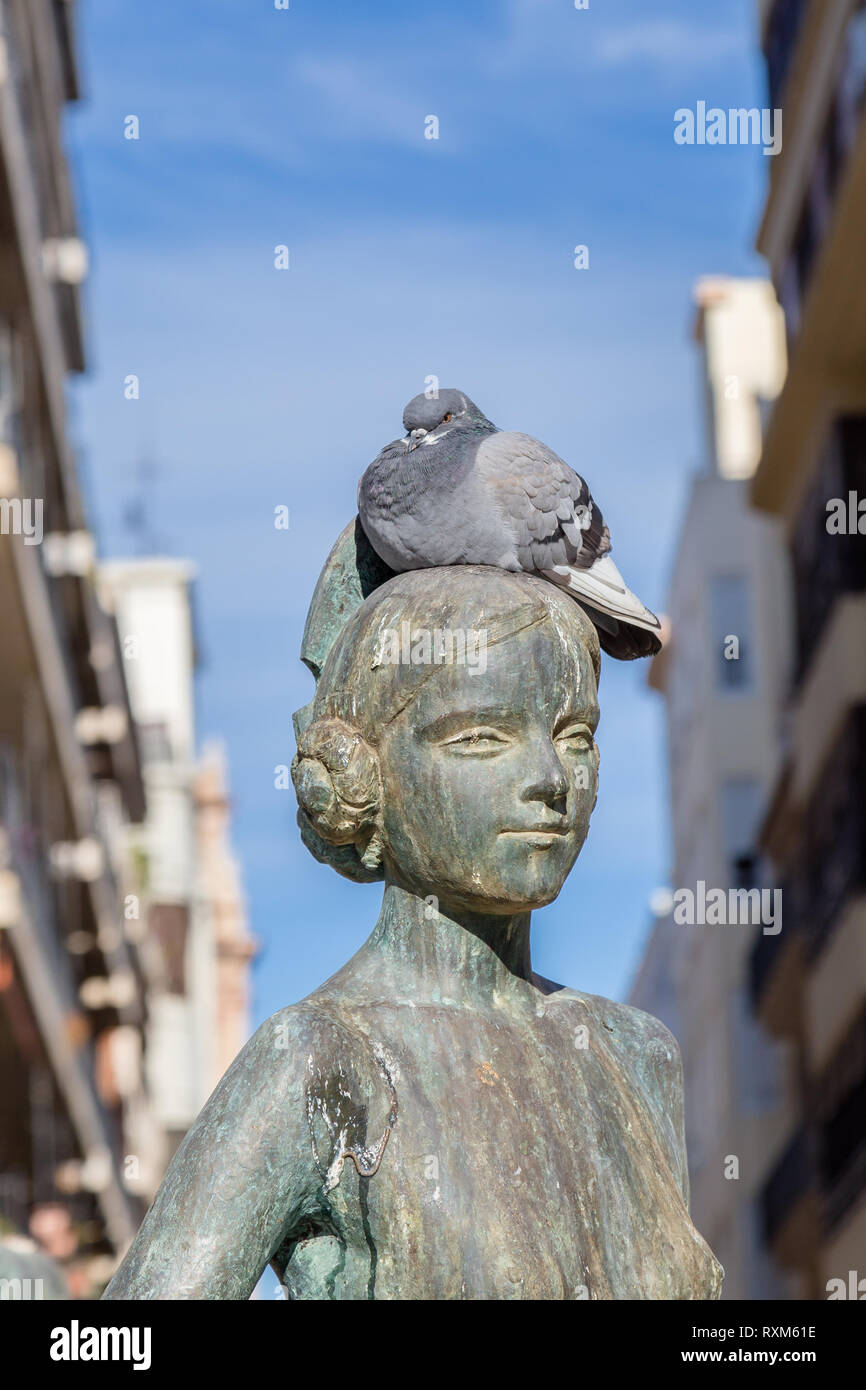 Valencia,Spain December 02, 2016: Pigeon on head of girl from historic fountain at Plaza de la Virgen in Valencia Spain. Stock Photo