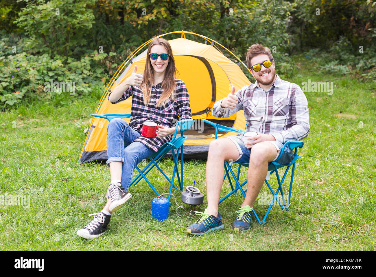people, summer tourism and nature concept - young couple sitting near a ...