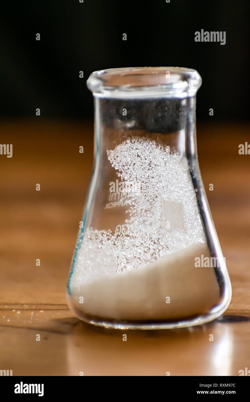 Erlenmeyer flask filled with sugar crystals. Some crystals cling to the sides of the flask giving nice refractive shine Stock Photo