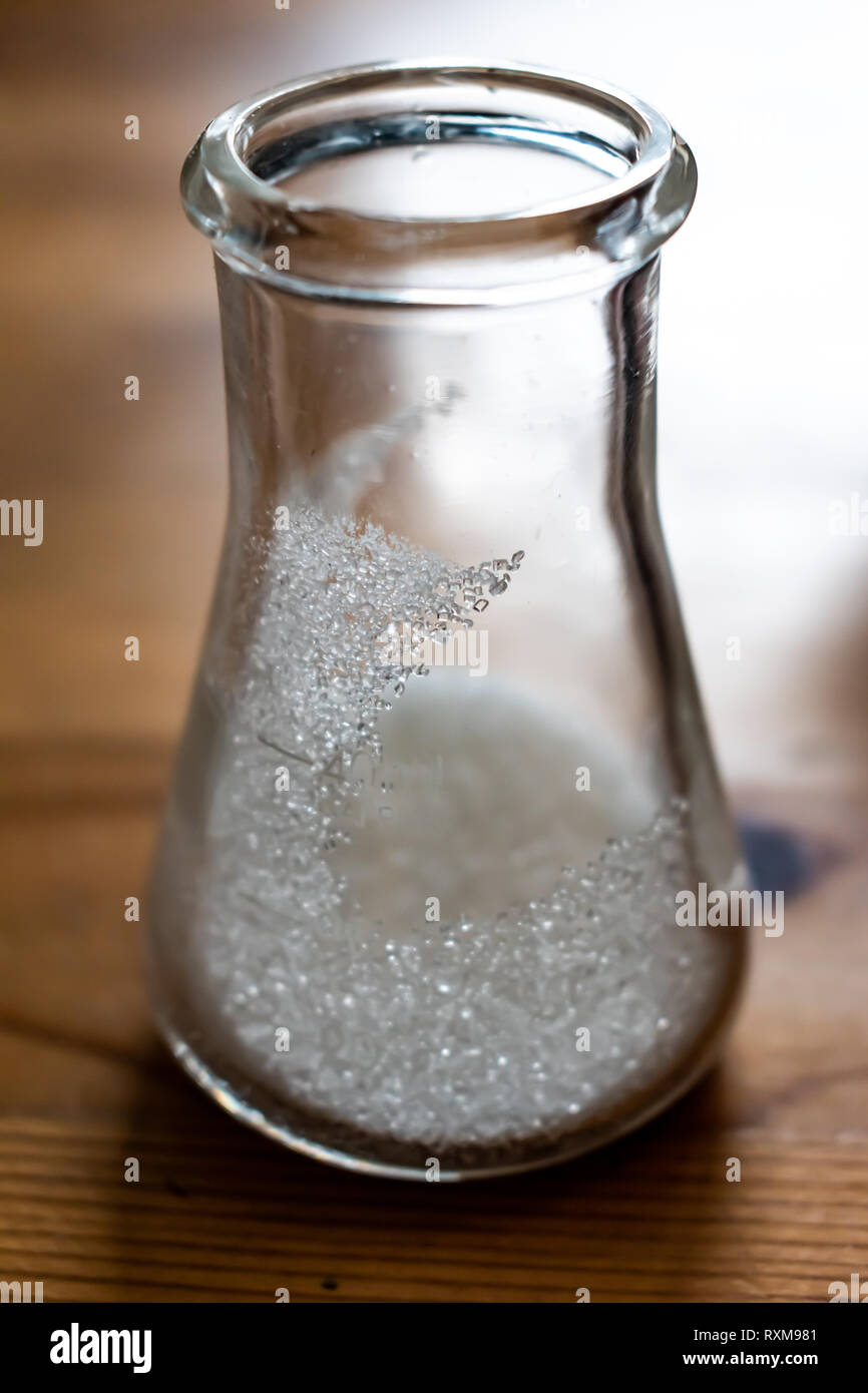erlenmeyer flask with table sugar crystals inside. Some crystals cling to the walls of the flask with some even being distinctly and uniquely visible Stock Photo