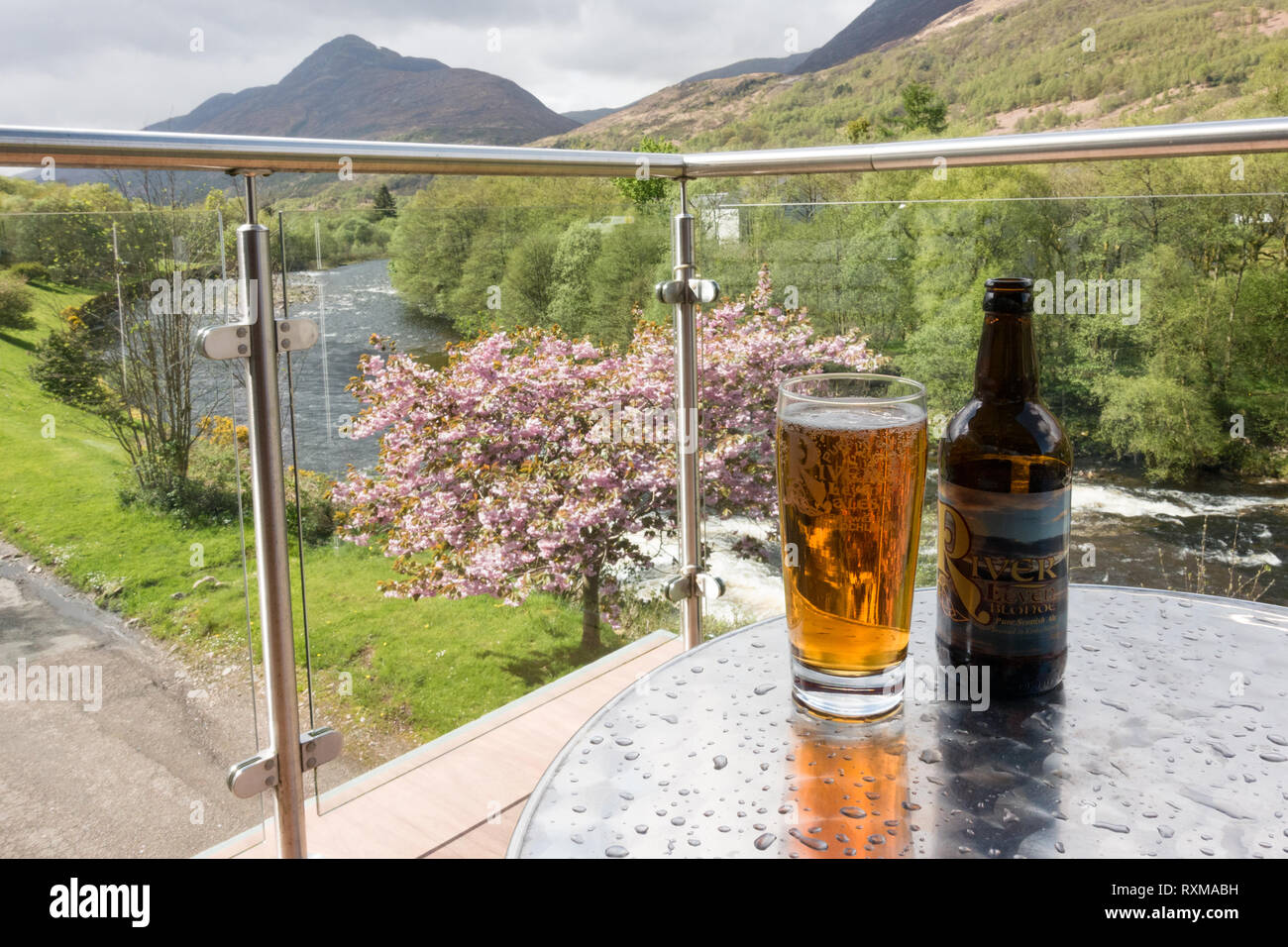 Glass of River Leven Blonde Ale, brewed in Kinlochleven on the balcony of the Highland Getaway Inn overlooking the River Leven, Kinlochleven, Scotland Stock Photo