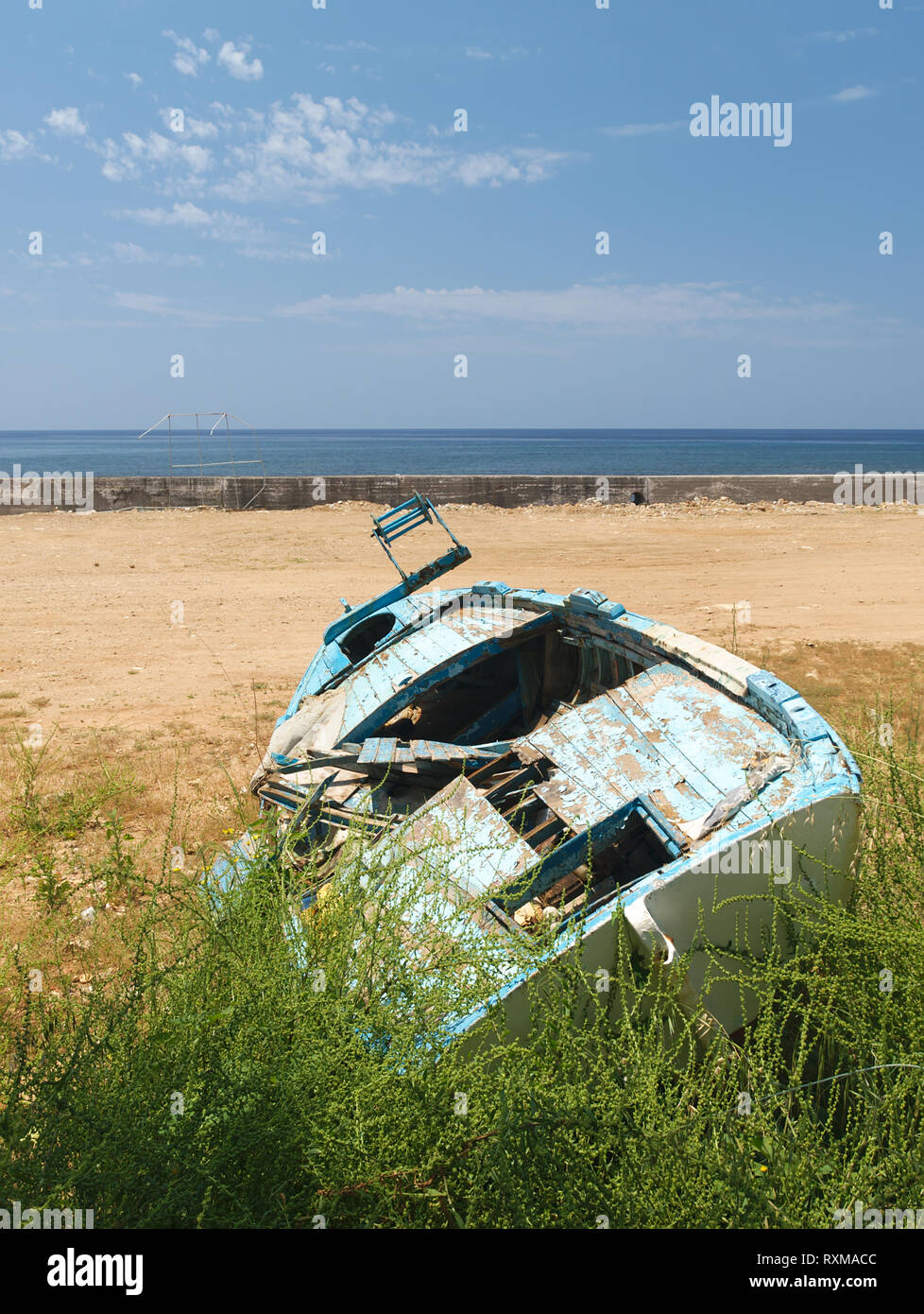 Blue broken abandoned old wooden boat tilted on land with grass with ...