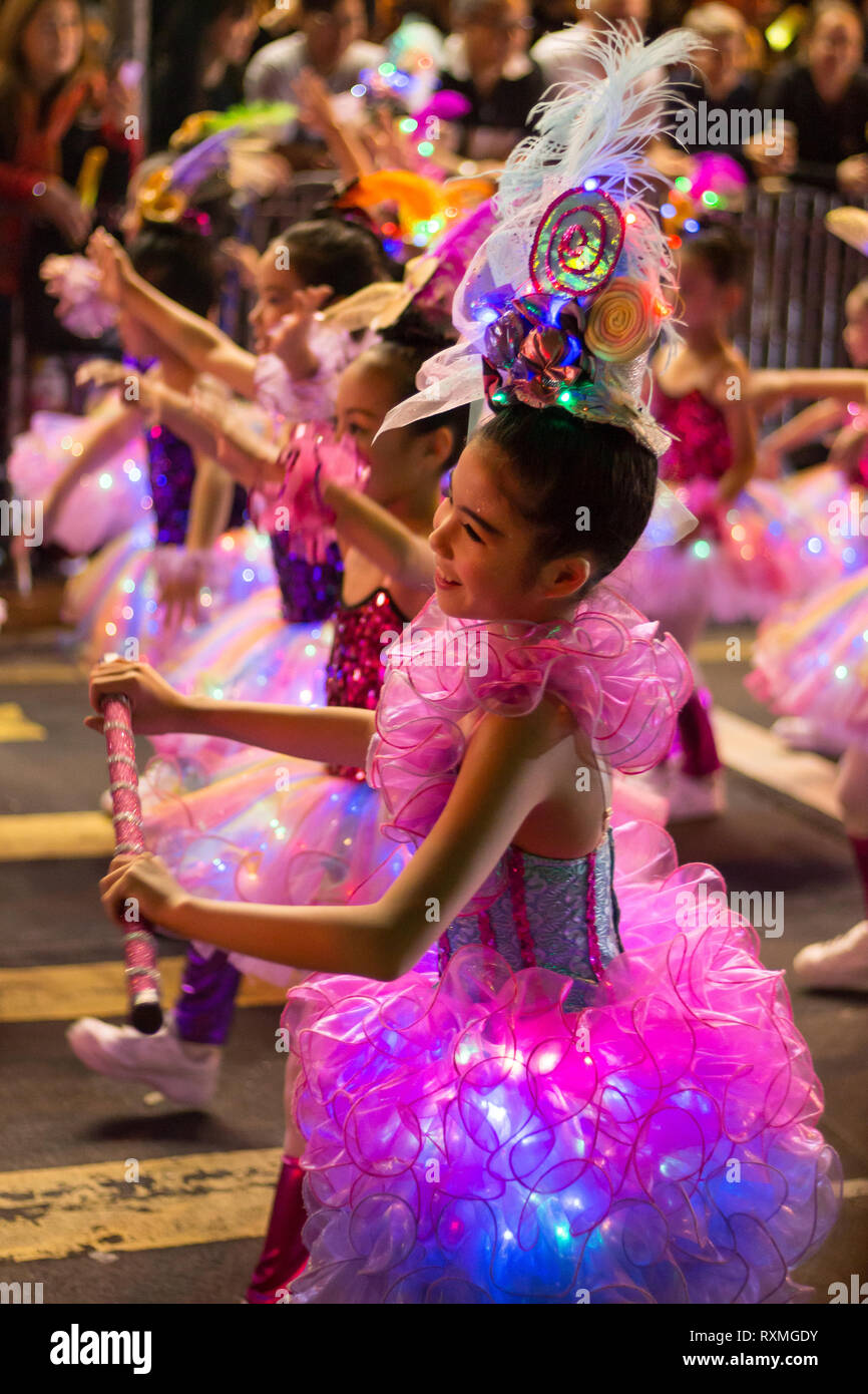 Girls in pink dresses dancing as part of the Chinese New Year / Lunar New Year celebrations (Year of the Pig) in Kowloon, Hong Kong, China Stock Photo
