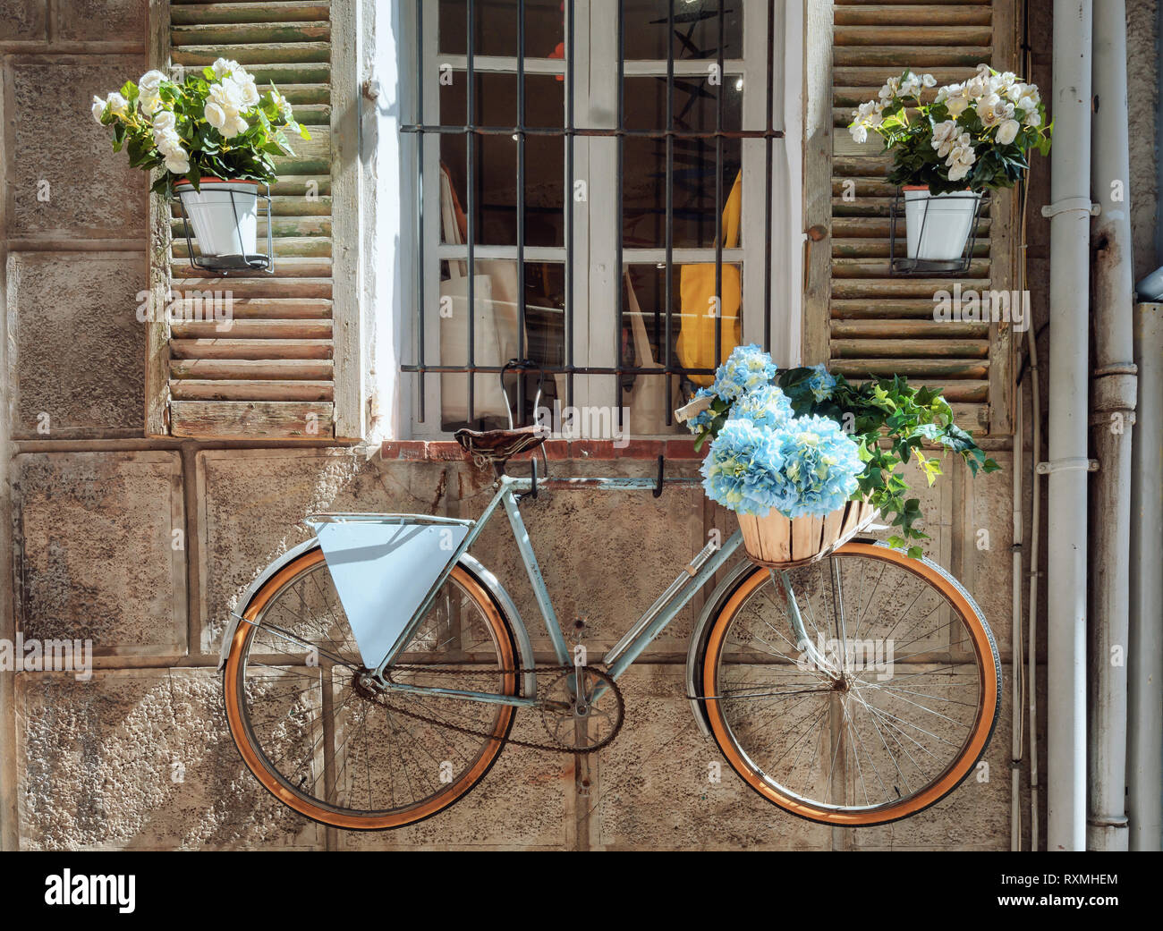Shutters of a house in the French town Antibes nicely decorated with colorful flower pots and the wall with a bicycle Stock Photo