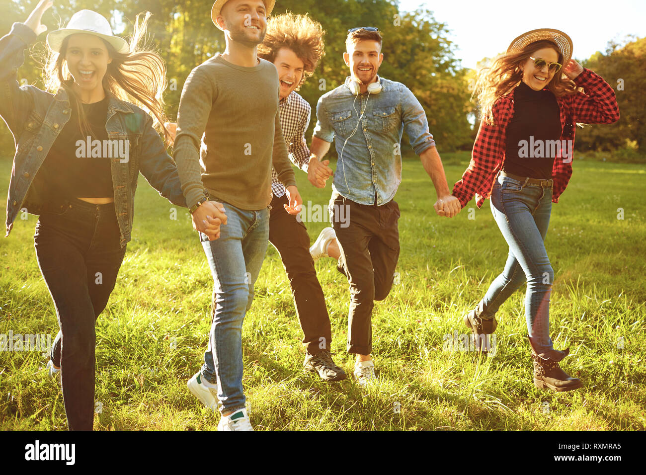 Cheerful friends are running in the park. Stock Photo