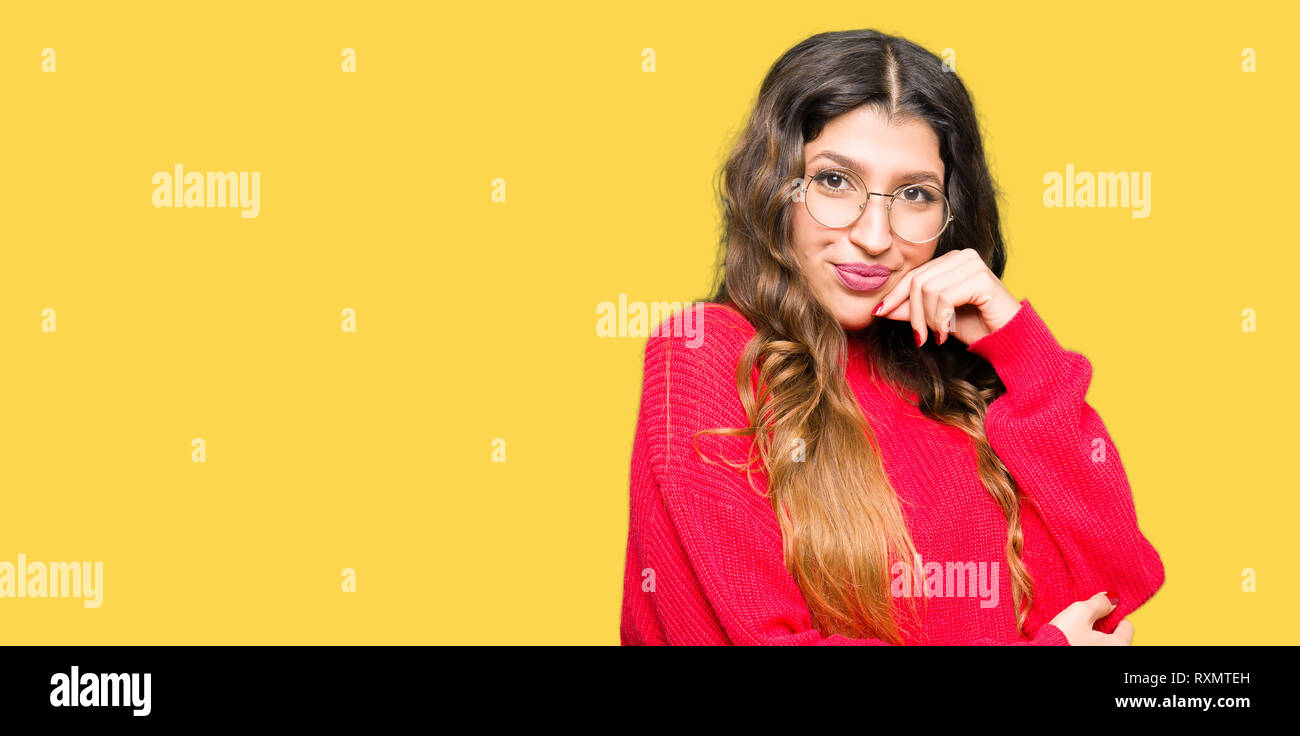 Young beautiful woman wearing red glasses with hand on chin thinking about question, pensive expression. Smiling with thoughtful face. Doubt concept. Stock Photo