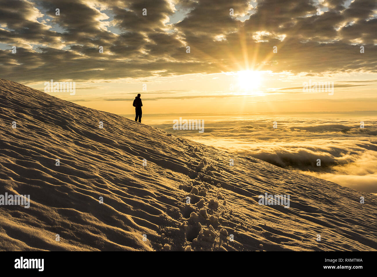 A silhoutte of a male climber enjoying the sunset on the slopes of Mount Baker, Washington, USA Stock Photo