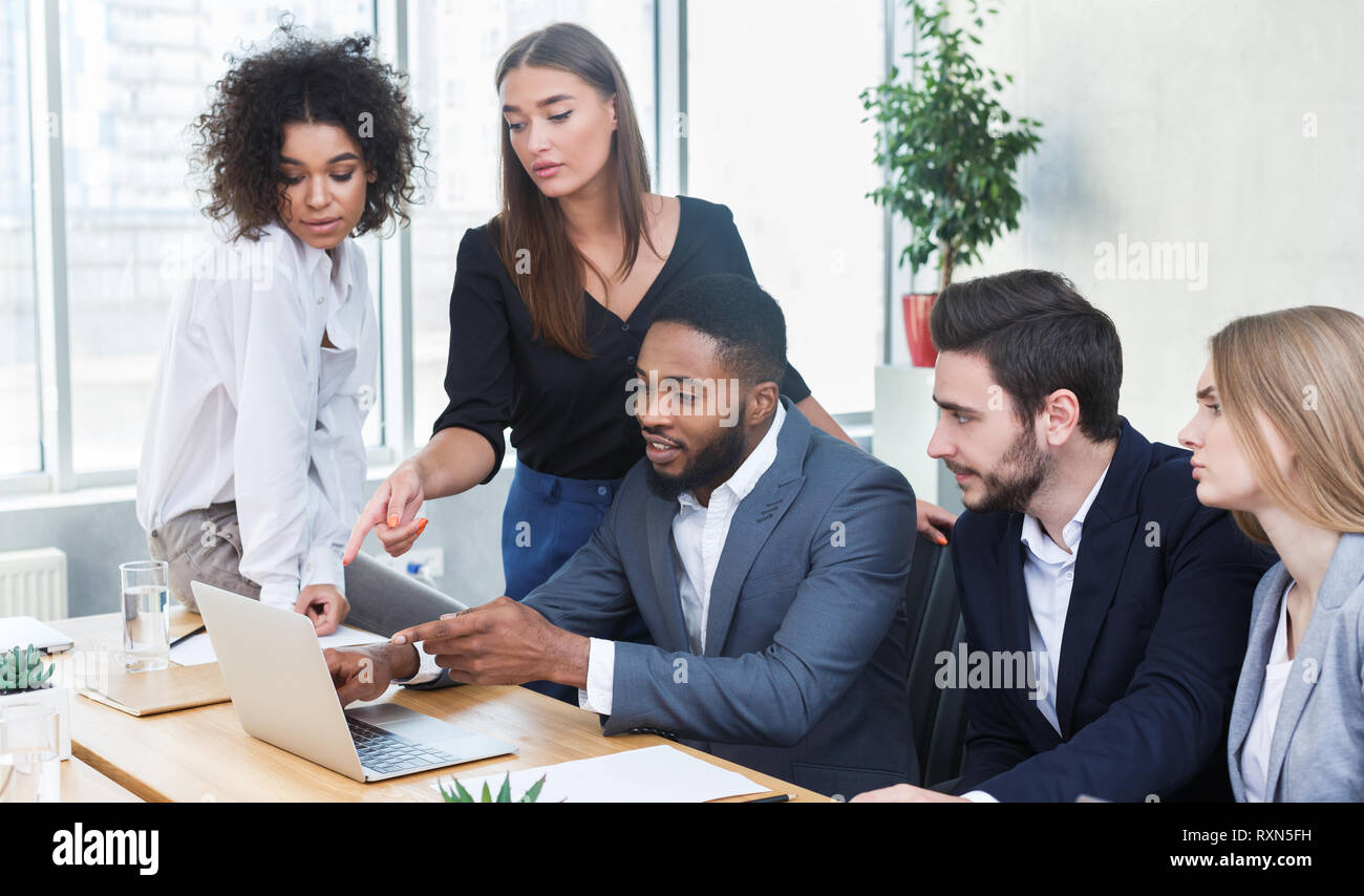 Business managers analyzing data on laptop at meeting Stock Photo