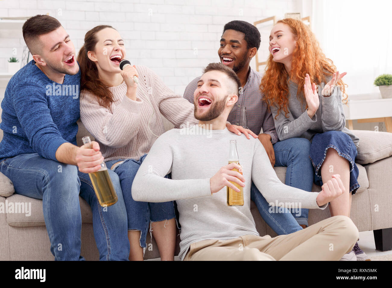 Friends singing karaoke, having party at home Stock Photo Alamy