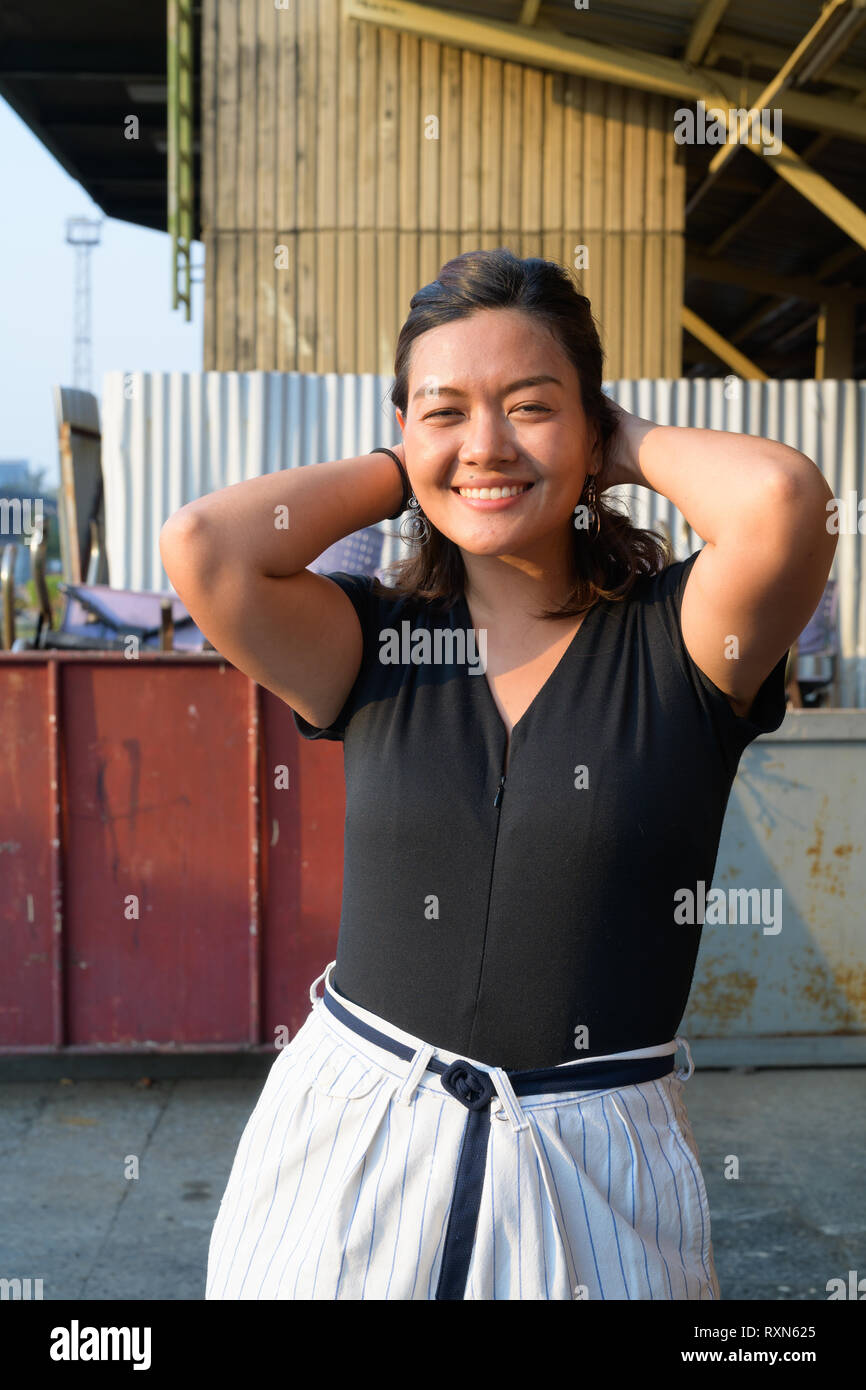 Happy young beautiful Asian woman smiling in urban street Stock Photo
