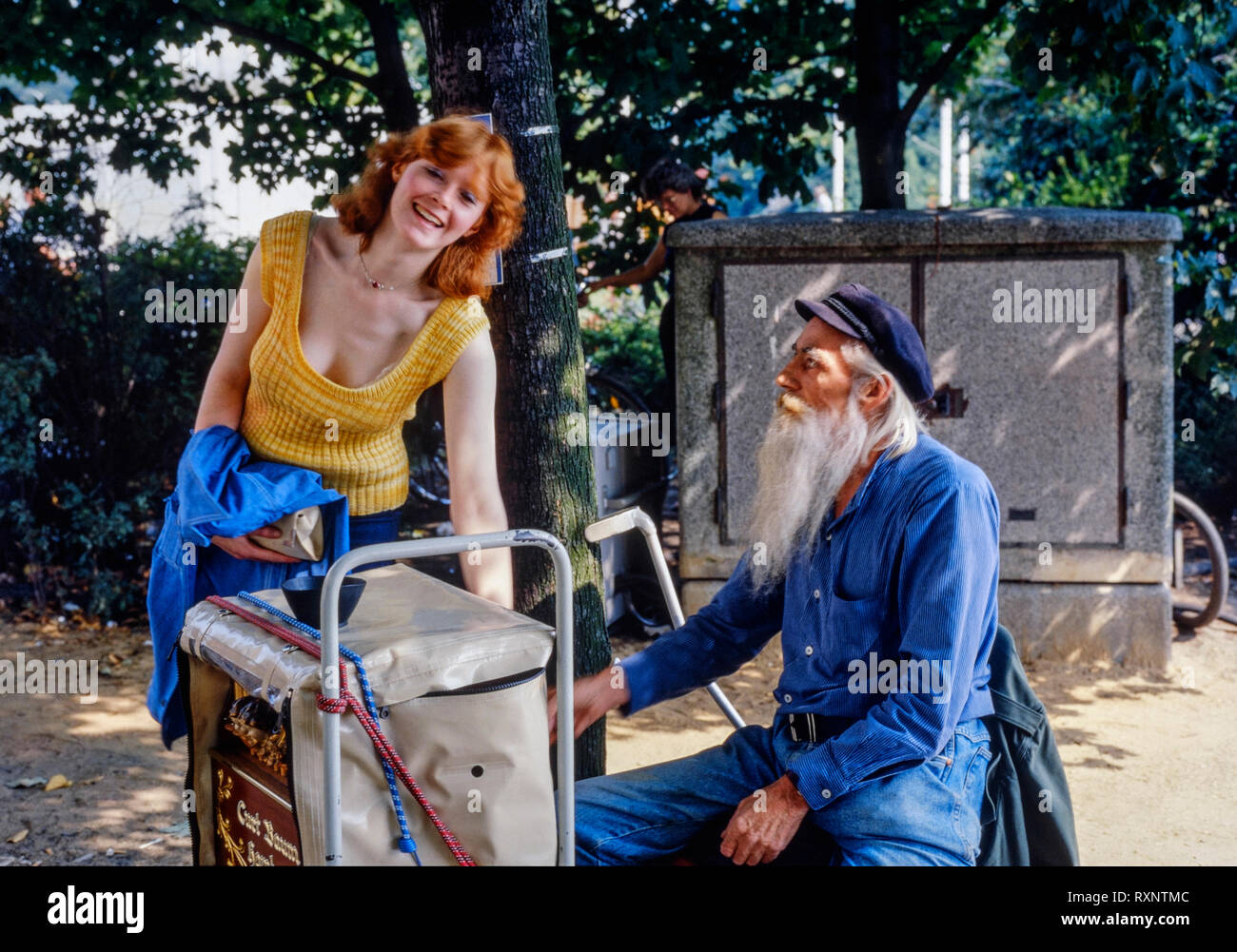 young smiling female tourist with a barrel organ and its operator in hamburg germany during the 1980s Stock Photo