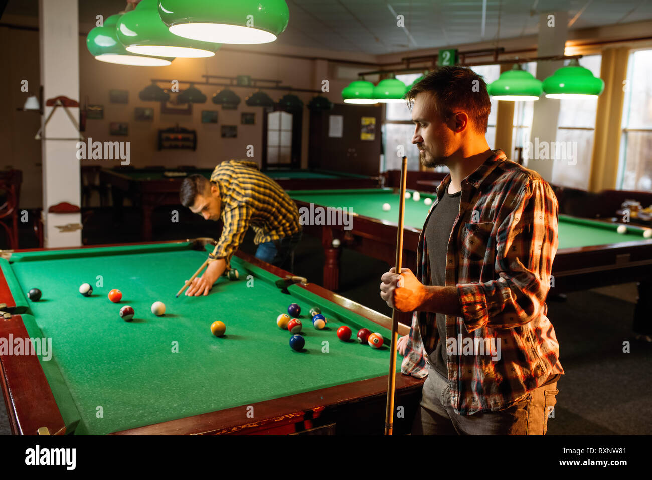 Two male billiard players with cues poses Stock Photo