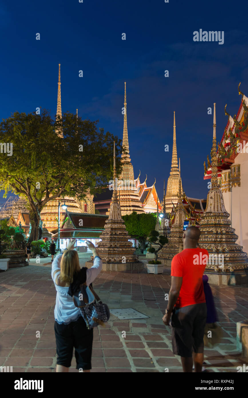 Tourists take photos of buddist temple Phra Maha Chedi at night, Bangkok, Thailand Stock Photo