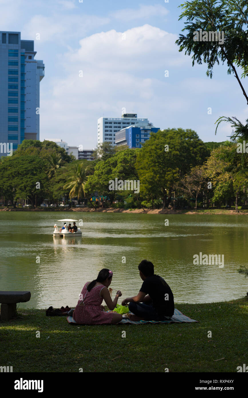 Tourists having a picnic near a lake in Lumpini park, Bangkok, Thailand Stock Photo
