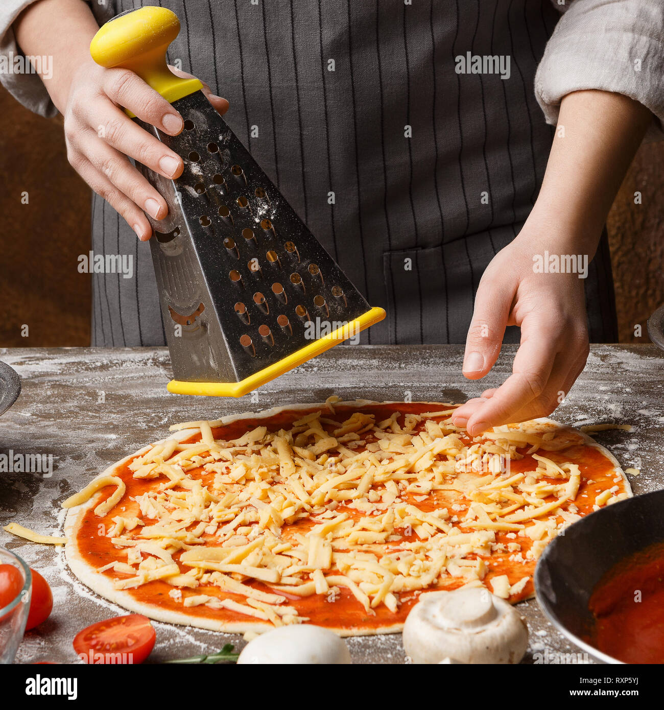https://c8.alamy.com/comp/RXP5YJ/pizza-preparation-woman-rubbing-cheese-on-grater-RXP5YJ.jpg
