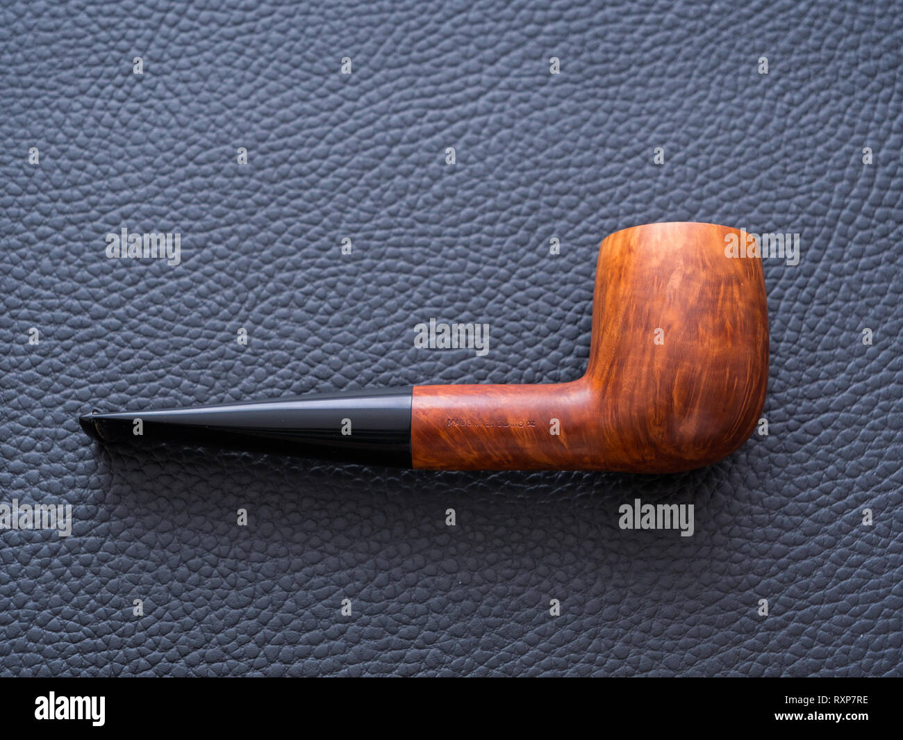 Beautiful and Expensive Light Brown Straight Grain Billiard Tobacco Pipe on a Black Leather Background - A Concept for Smoking Stock Photo