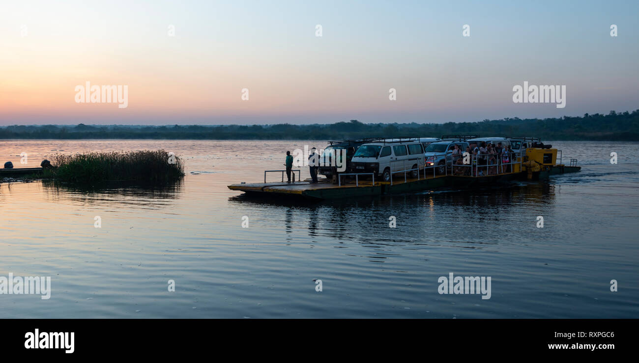 Dawn shot of ferry transporting vehicles and people across Victoria Nile river at Paraa in Murchison Falls National Park, Northern Uganda, East Africa Stock Photo