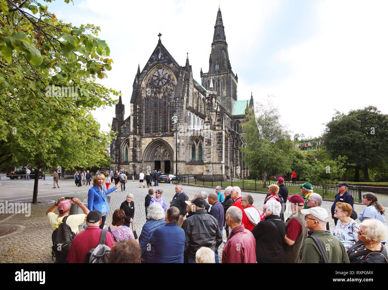 Tour guide adressing tourists in front of Glasgow Cathedral, sometimes referred to as the High Kirk of Glasgow or St Mungo's Cathedral, Glasgow, Scotland Stock Photo