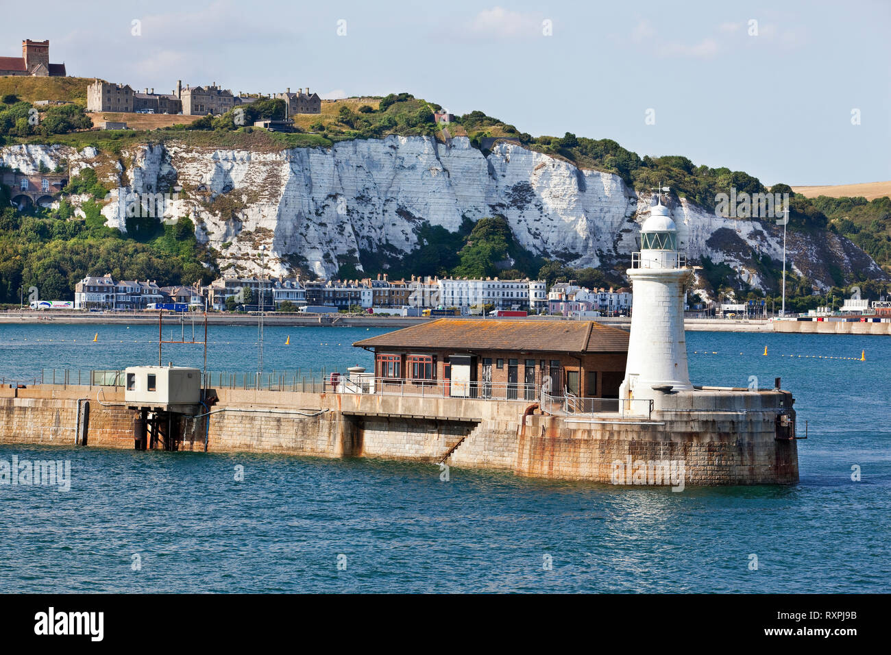 Northern cliffside of Dover on top of which is a partial view of Dover Castle. In the foreground is the Dover West End Breakwater Lighthouse, Dover, United Kingdom Stock Photo