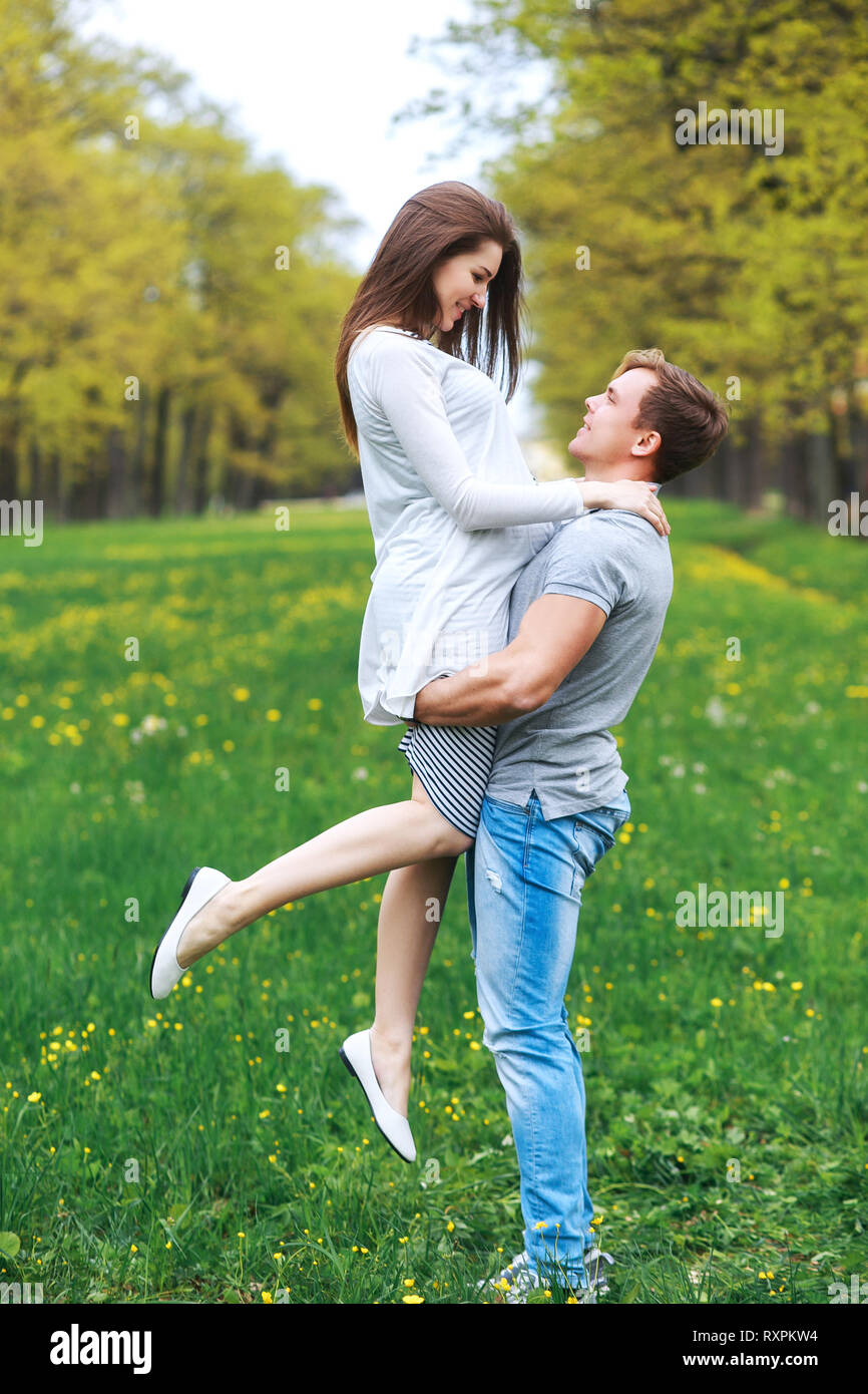Man carrying his pregnant woman in park.Portrait of lovely future parents in sunny day in park Stock Photo