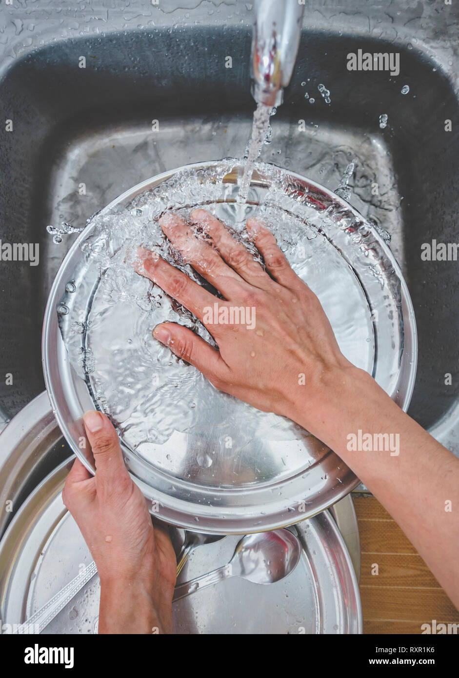 Personal perspective view of hands wash utensils over the sink in kitchen Stock Photo