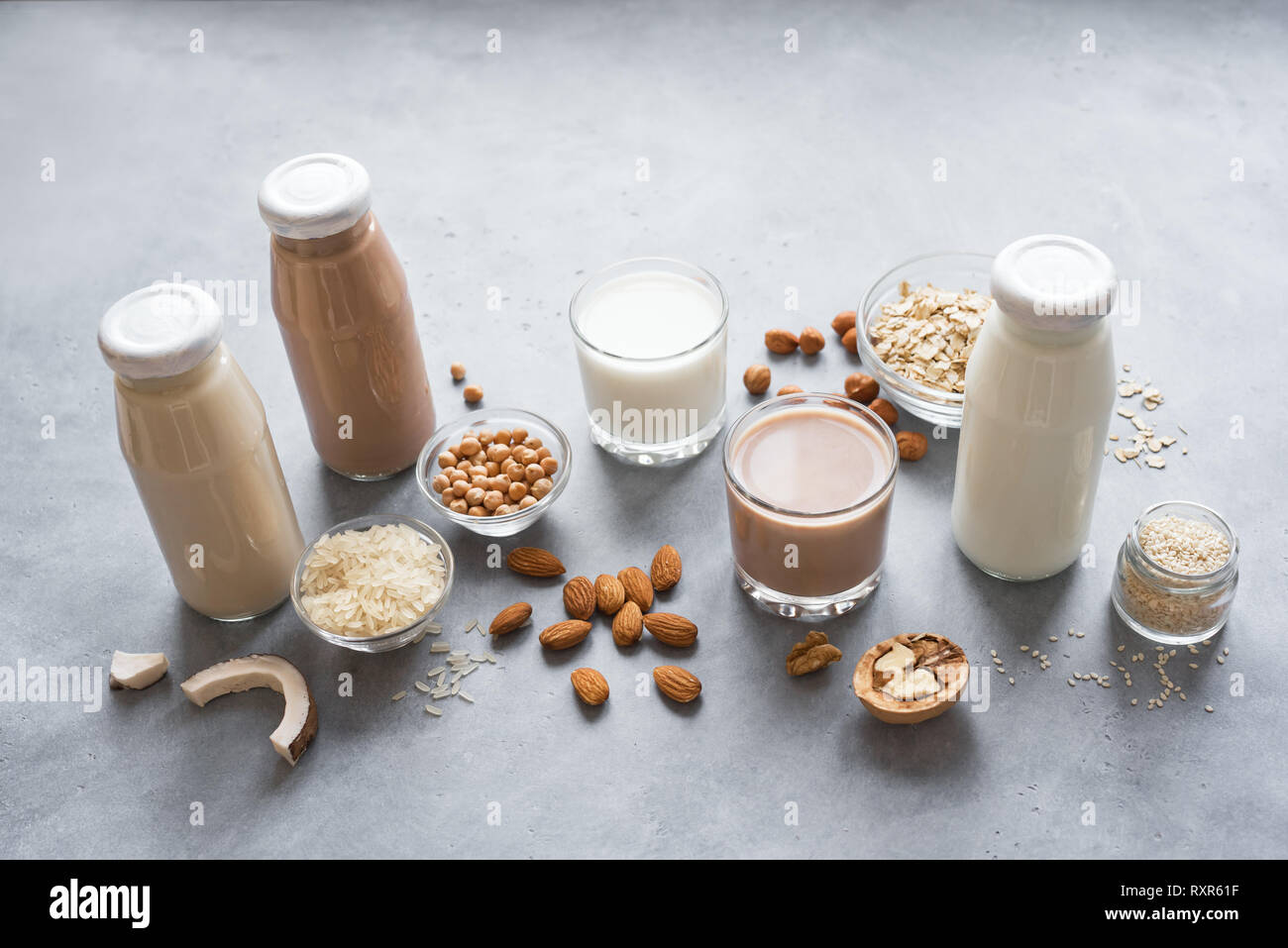 Various vegan plant based milk and ingredients on grey, copy space