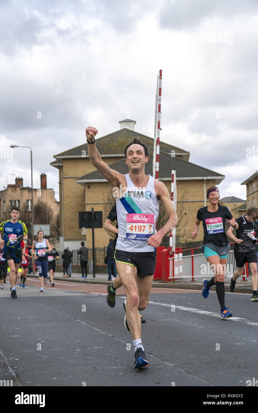 London, UK. 10th Mar 2019. An athletic man celebrates his way to the finish line in fundraising charity event Vitality Big Half marathon. Credit: AndKa/Alamy Live News Stock Photo