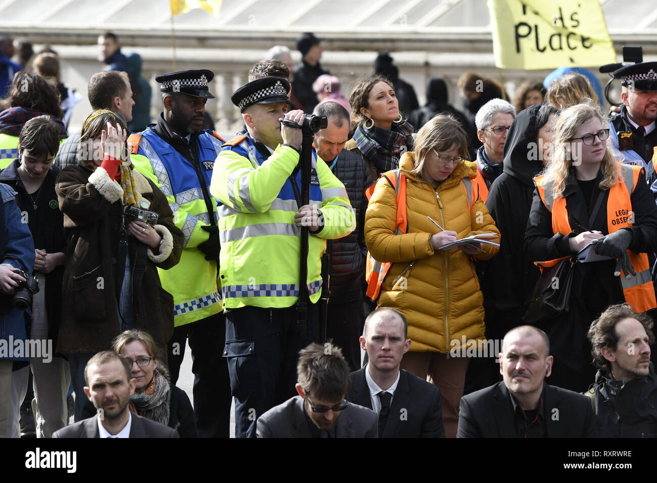 London, Greater London, UK. 9th Mar, 2019. Police officers recording Extinction Rebellion activists outside Downing Street.Hundreds of activists from the Extinction Rebellion climate change movement gathered at Parliament Square, marched to Downing Street, and poured 200 litres of fake blood on the ground. This act of non-violent civil disobedience was carried out to demand from the government direct actions to reduce carbon emissions to zero by 2025, speak the truth about climate change and call for a national citizen's assembly. For the activists, carrying buckets of 'blo Stock Photo