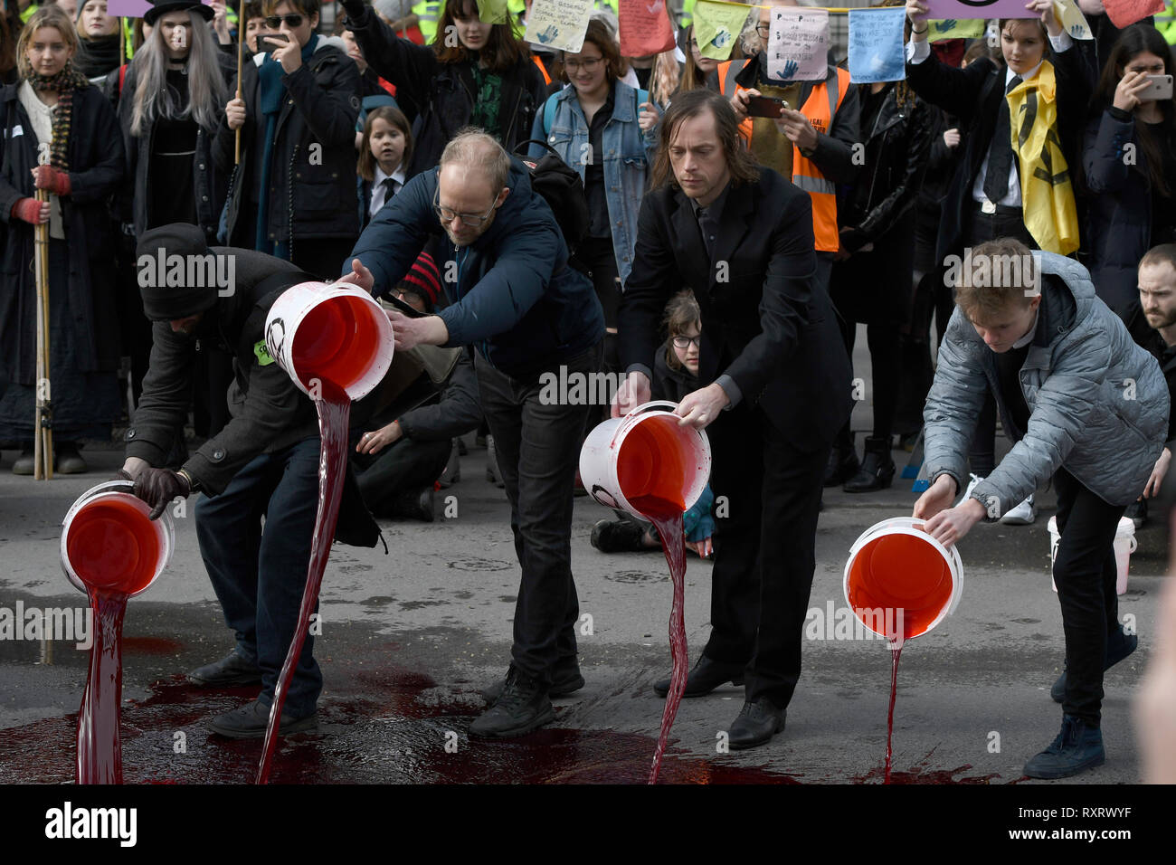Extinction Rebellion activists pouring buckets of fake blood outside Downing Street.  Hundreds of activists from the Extinction Rebellion climate change movement gathered at Parliament Square, marched to Downing Street, and poured 200 litres of fake blood on the ground. This act of non-violent civil disobedience was carried out to demand from the government direct actions to reduce carbon emissions to zero by 2025, speak the truth about climate change and call for a national citizen’s assembly. For the activists, carrying buckets of “blood” to Downing street and spilling it symbolised the viol Stock Photo