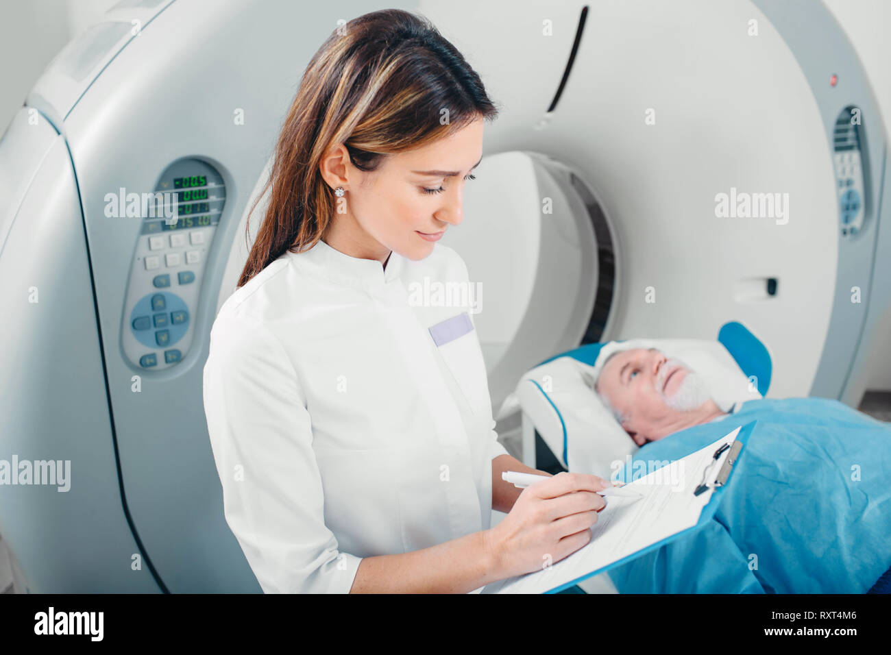 Radiologist write into medical chart after CT Scan Stock Photo