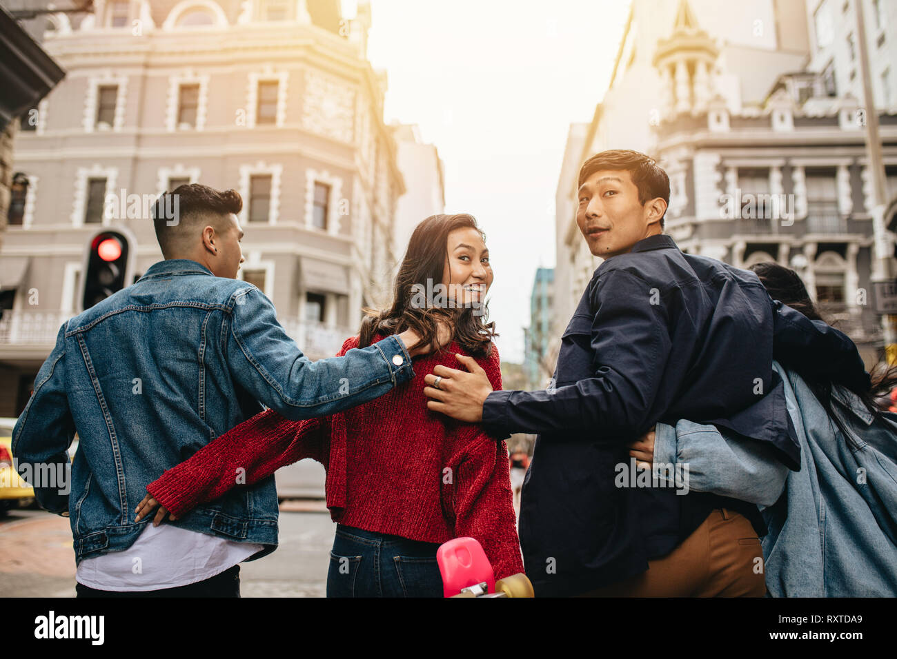 Rear View Of Friends Walking Together Outdoors With Arms Around With Couple Looking Back Group Of Asian Men And Women Hanging Out RXTDA9