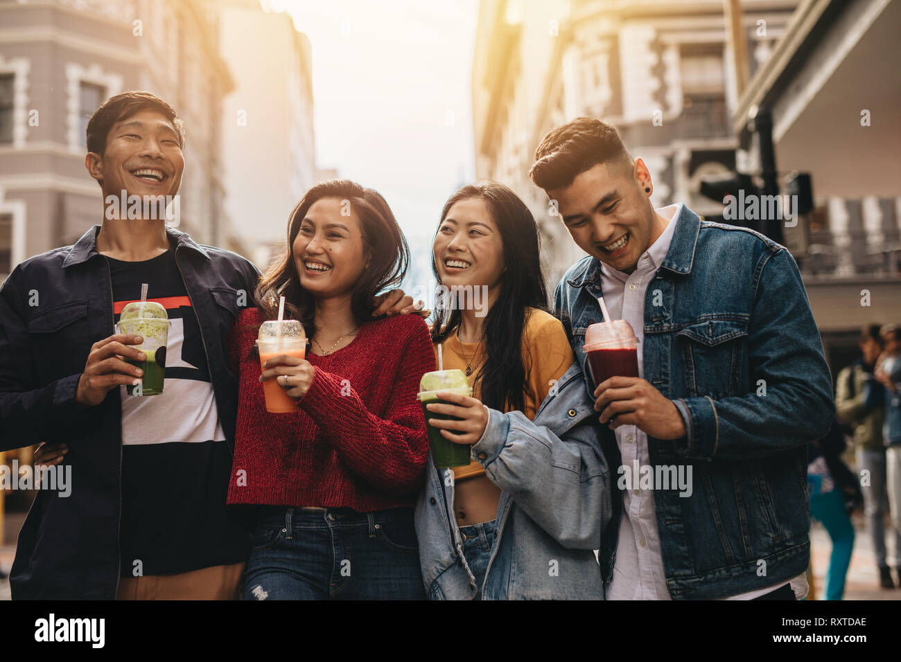 Group of young asian people walking on the city street with juice. Multi-ethnic young men and women on city street with juice. Stock Photo