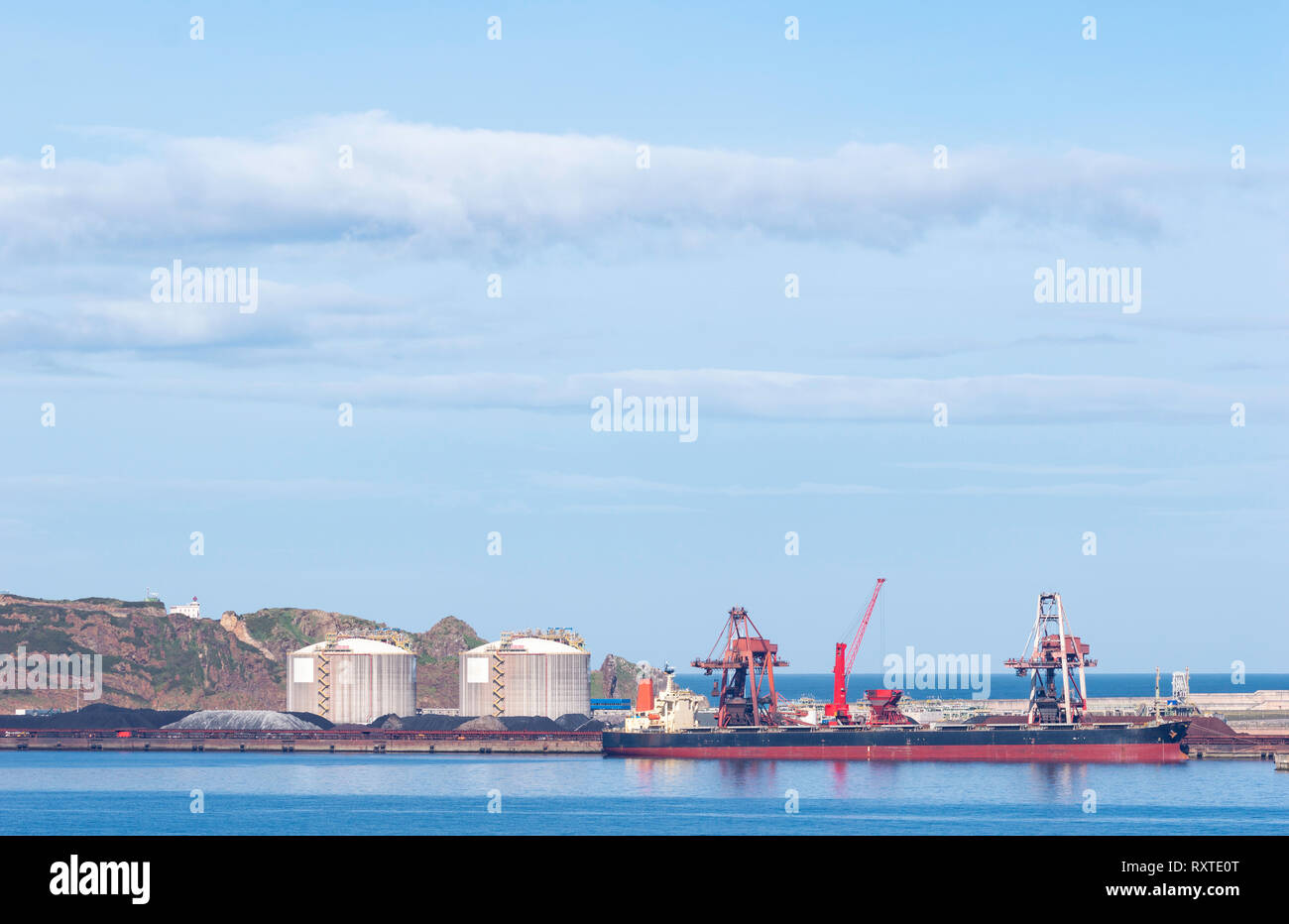 Coal cargo ship moored in port with lifting cargo cranes, ships and grain. Gijón, Asturias, Spain. Stock Photo