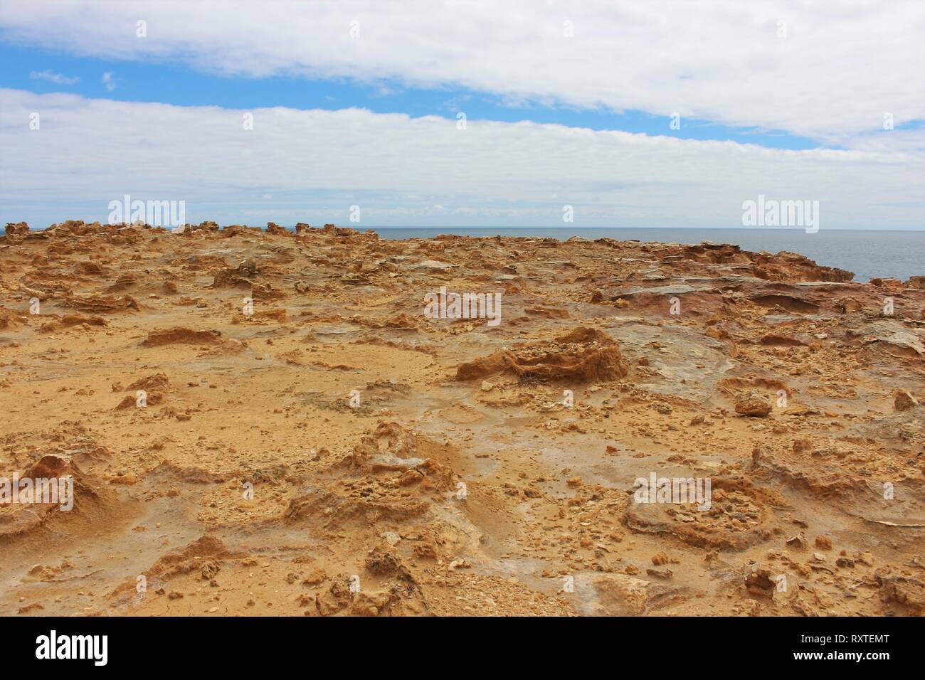 Barren dusty rock formations at the petrified forest on the south coast of Australia, with the ocean in the background. Stock Photo