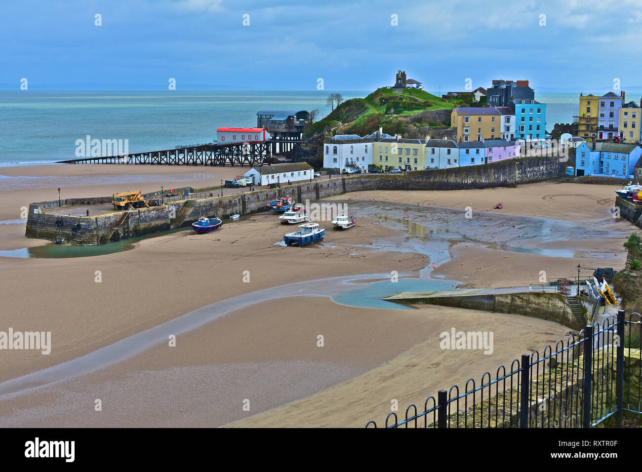 The pretty harbour at Tenby, low tide in Winter. Lifeboat stations old & new with pastel coloured houses overlooking the sandy North Beach.S.Wales Stock Photo