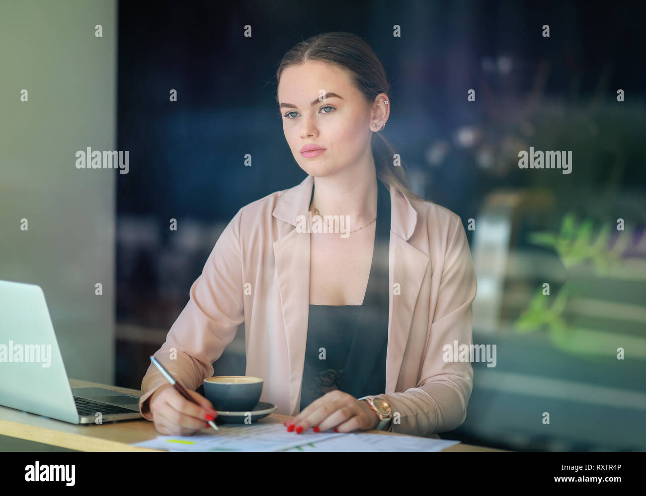 Elegant business woman looking through the window in a cafe shop. Thoughtful Look. Selective focus and reflexion on window Stock Photo