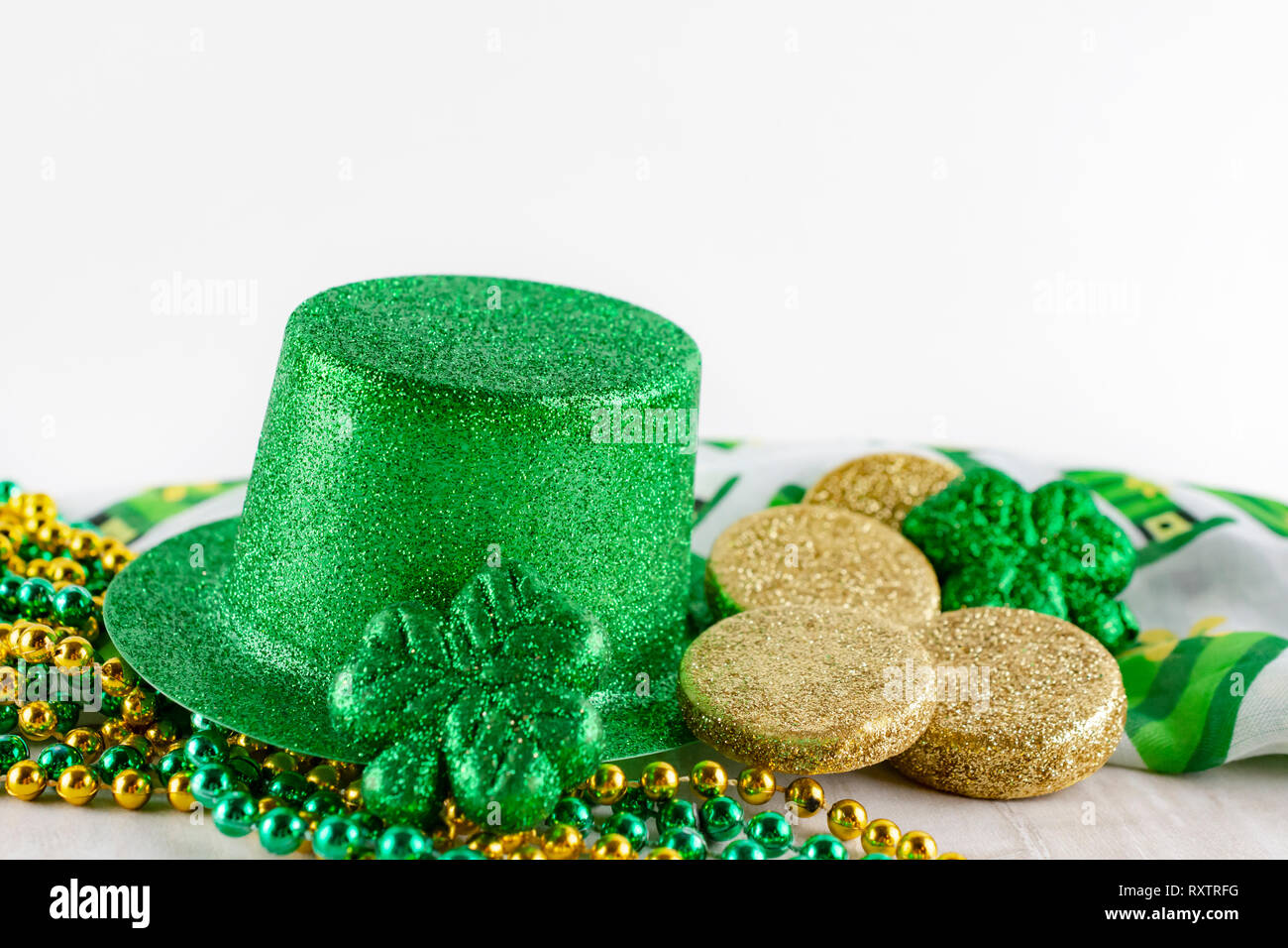 Saint Patrick's Day green top hat with gold coins, gold and green beads, green shamrock, and colorful scarf.  White background.  Plenty of copy space. Stock Photo