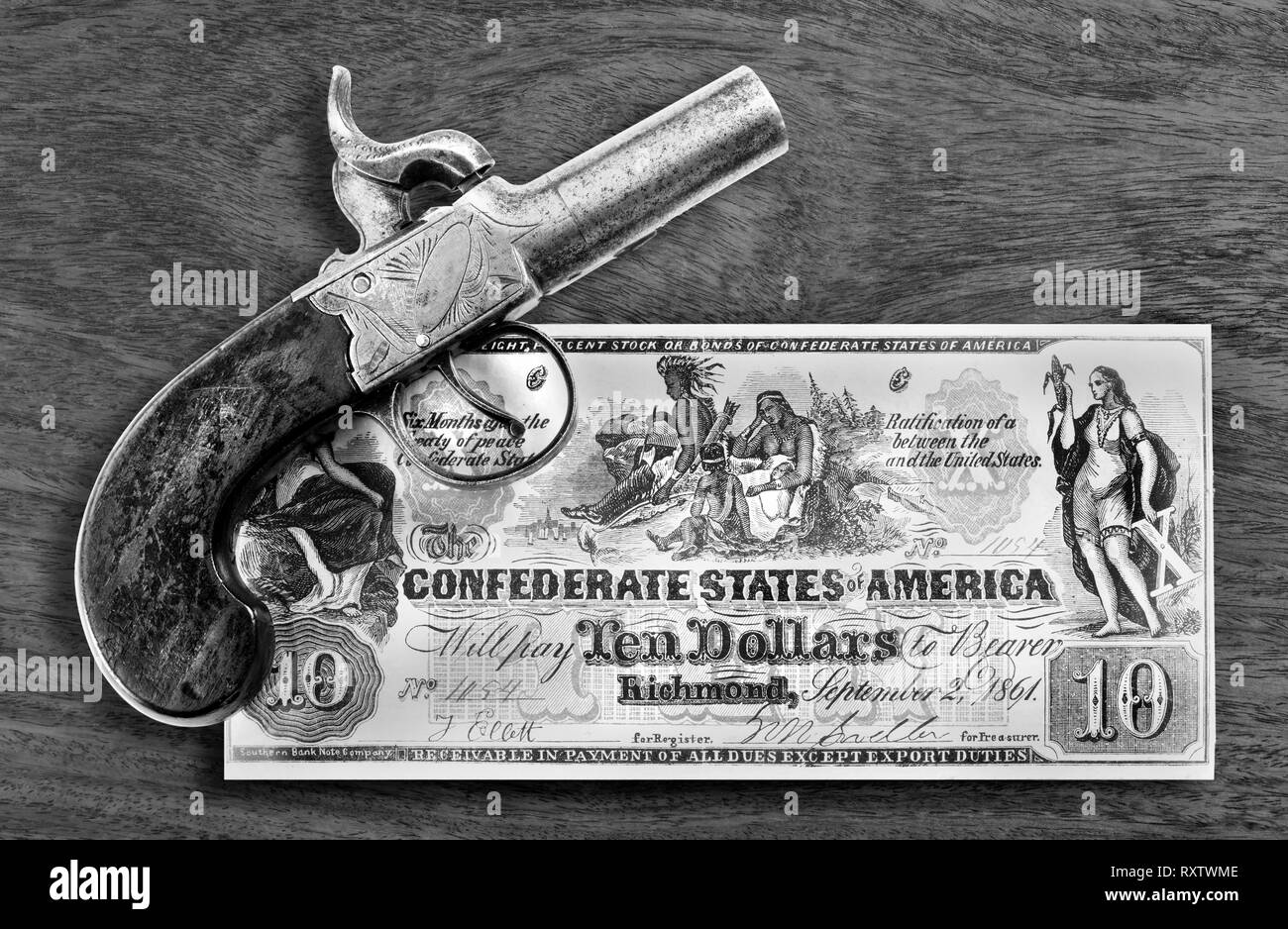 Antique percussion pistol and 1861 Confederate ten dollar bill in black and white. Stock Photo