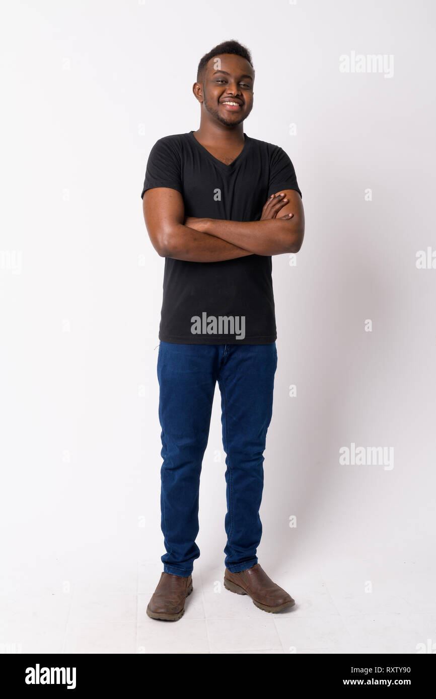 Full body shot of happy young African man smiling with arms crossed ...