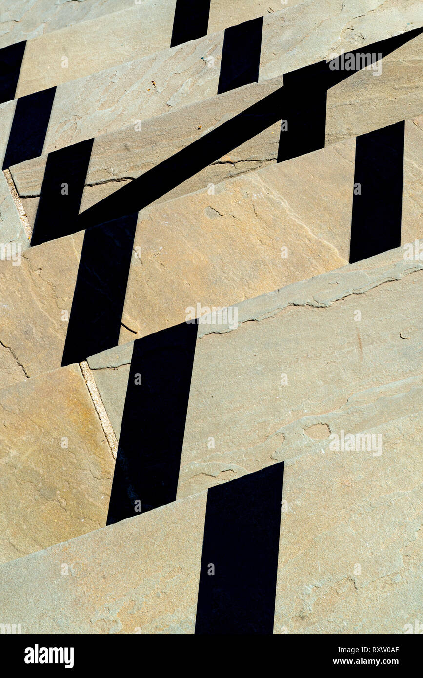 Shadows from railing, cast by sun on flagstone steps Stock Photo