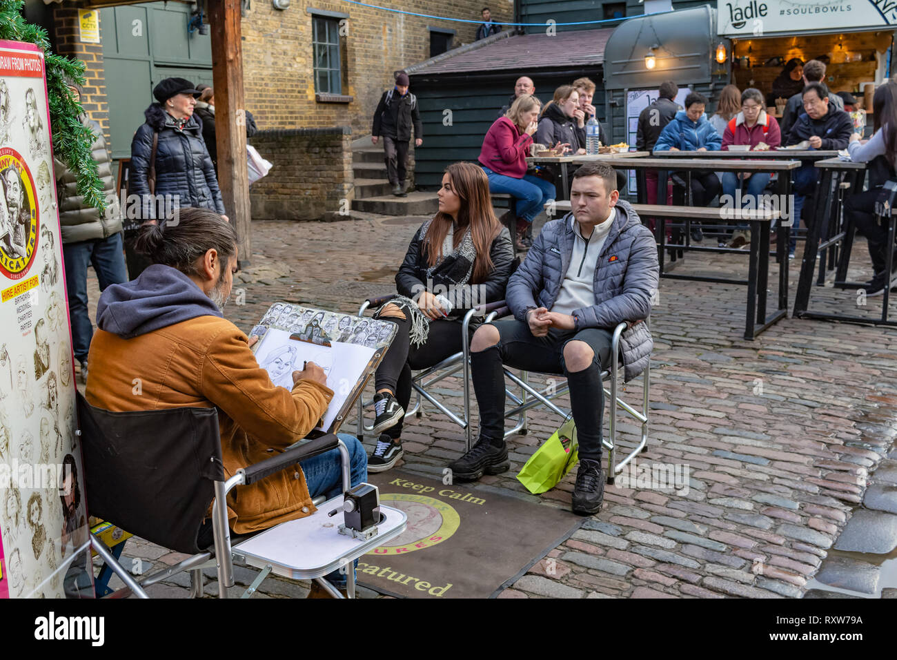 London, UK - 20, December 2018: Artist drawing caricatures of an british couple in Camden Lock Market or Camden Town in London, England, United Kingdo Stock Photo