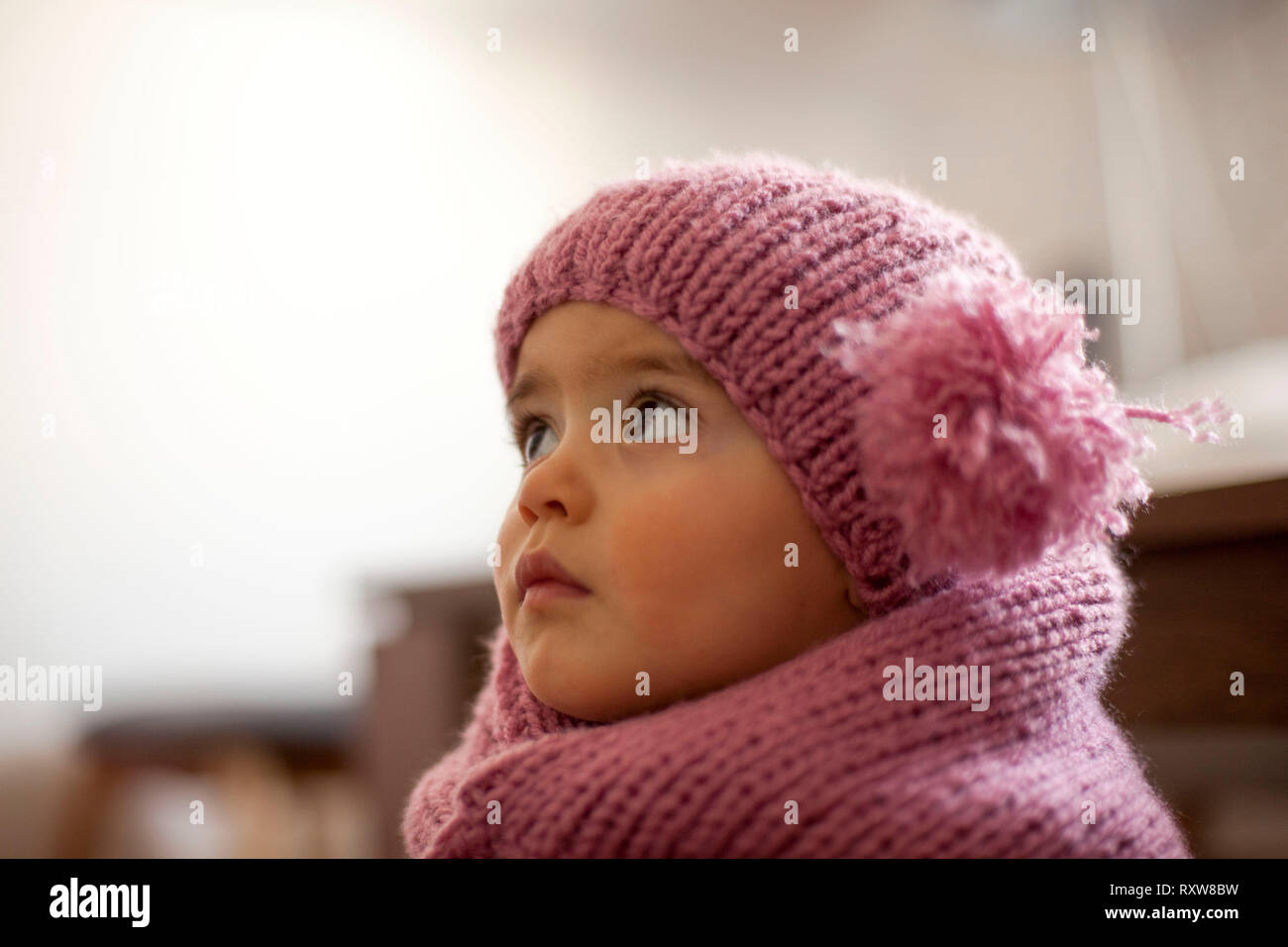 Cute little baby girl wearing purple woolen cap and warm scarf Stock Photo