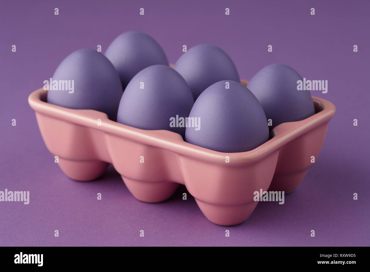 Pink ceramic egg tray with purple painted Easter eggs on purple