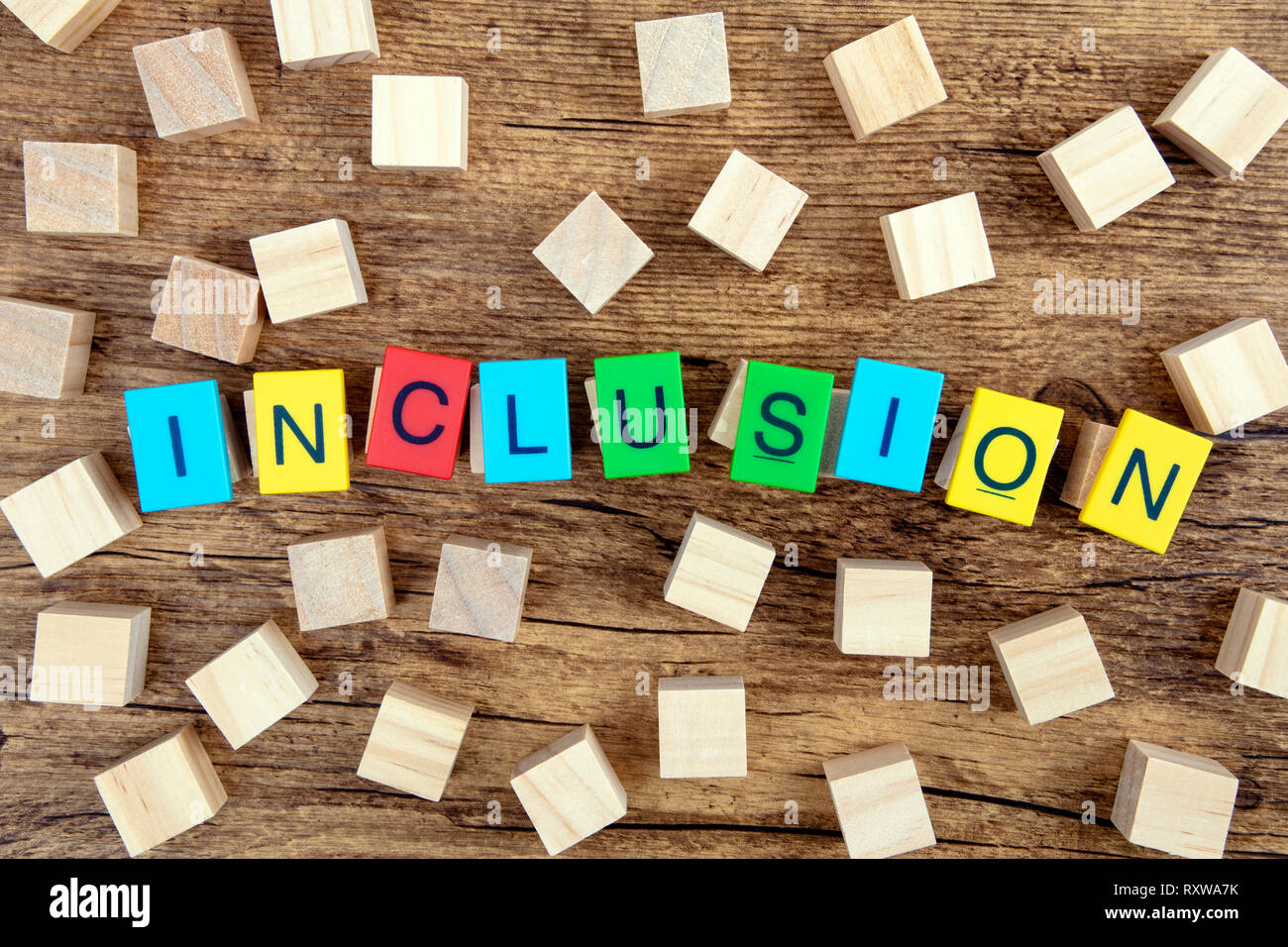Concept: Inclusion with colorful Toy Letters and wooden cubes on dark background Stock Photo