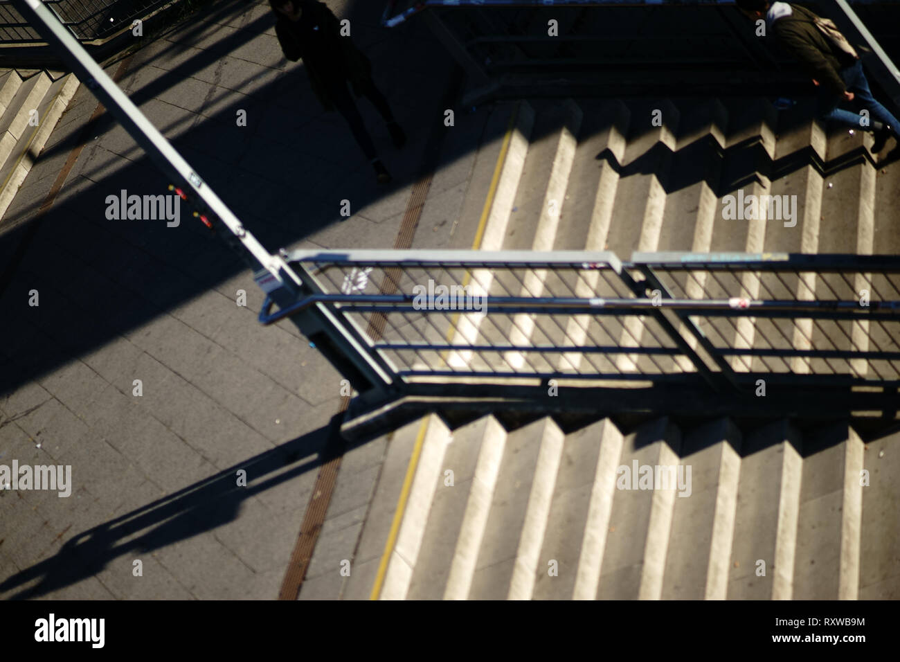 The top view of a sloping staircase with the shadow of a pedestrian on the stairs. Stock Photo