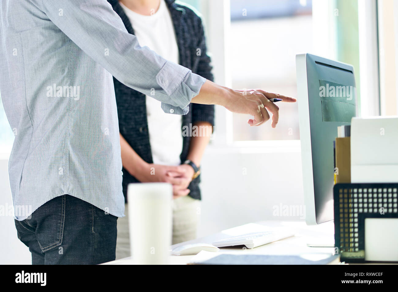 two young asian corporate executives working together using desktop computer. Stock Photo