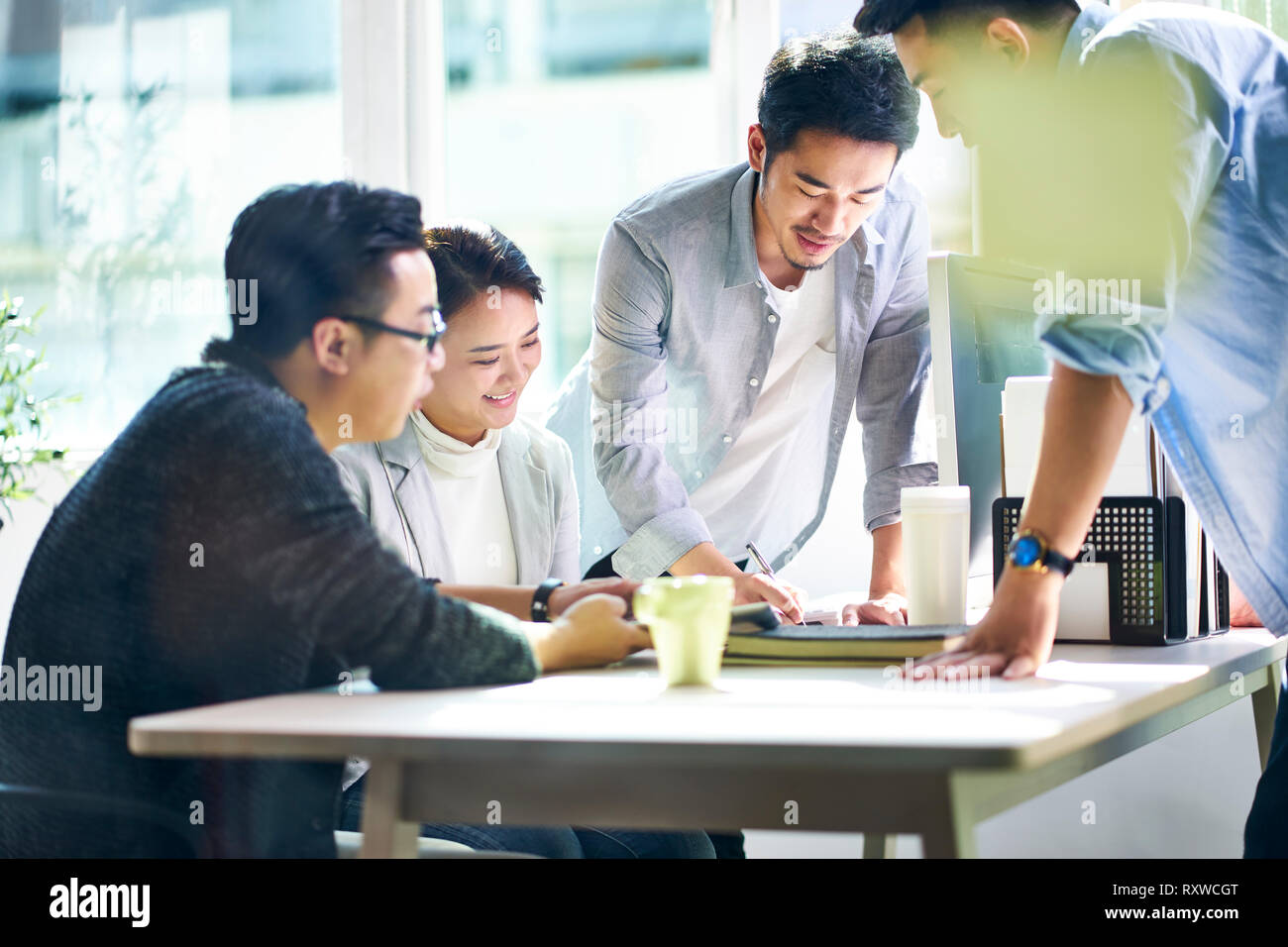 group of four young asian corporate executives meeting in office discussing business in office. Stock Photo