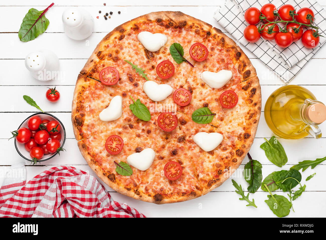 Hot Italian Pizza With Heart Shaped Mozzarella, Tomatoes, Cheese And Green Salad Leaf. Top View. Food Flat Lay Stock Photo