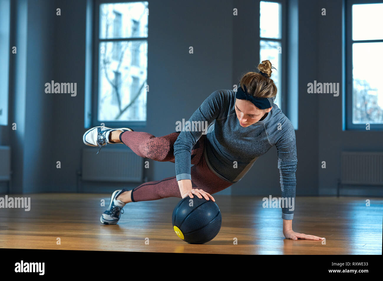 Fit and muscular woman doing intense core workout with kettlebell in gym. Female exercising at