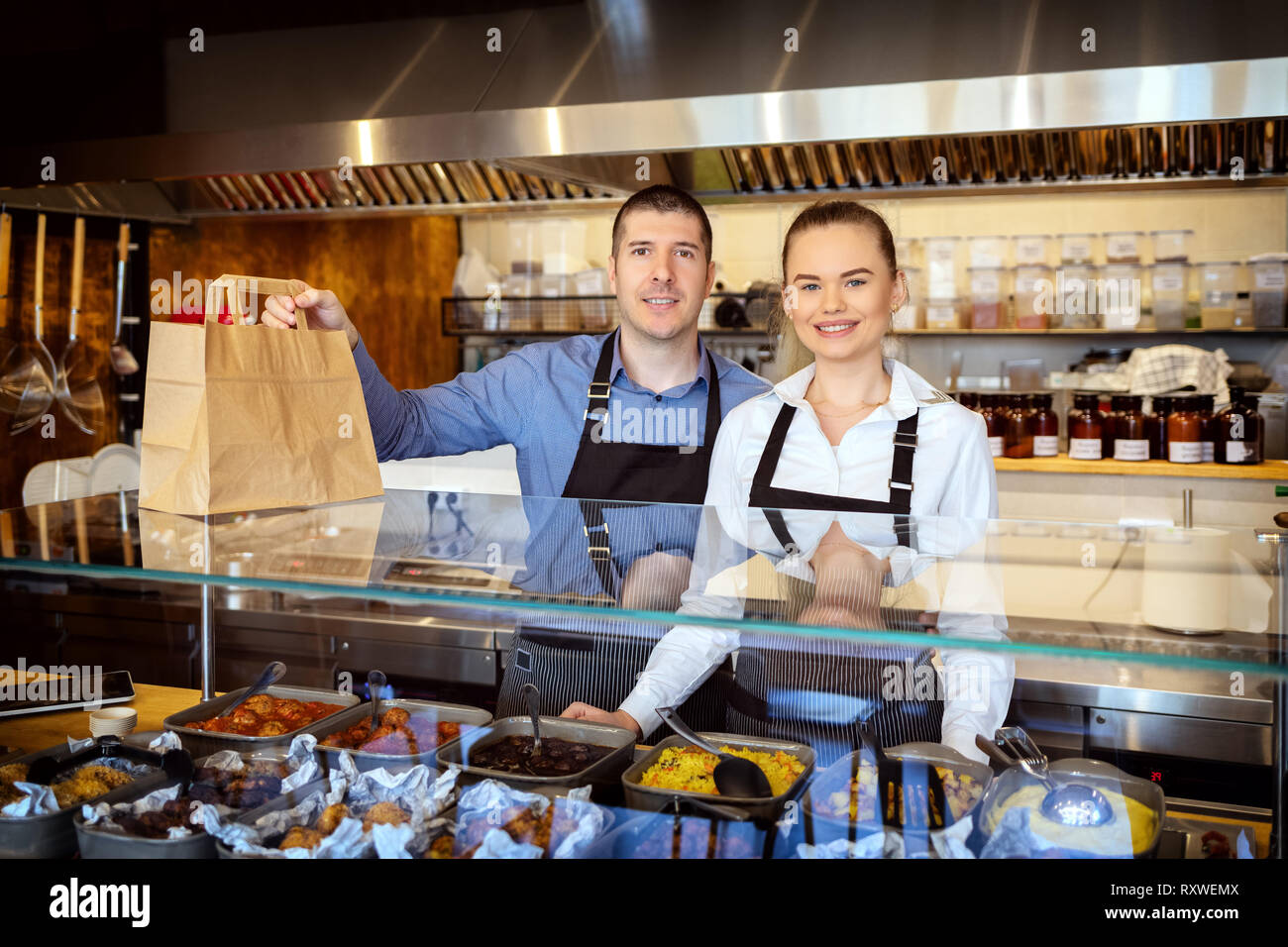 Catering services with waiters behind counter serving takeaway food Stock Photo